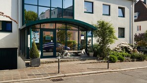 Un hotel con fachada moderna, amplias ventanas y acceso cubierto.