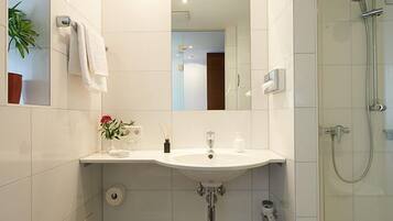A modern bathroom with a white sink, mirror, and shower.
