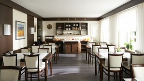 Un comedor amplio con varias mesas y sillas, una isla de cocina central y un gran ventanal que proporciona luz natural.