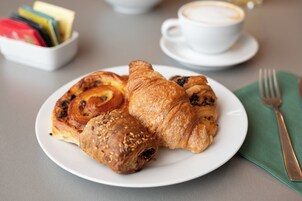 Un plato de cruasanes y una taza de café sobre una mesa.