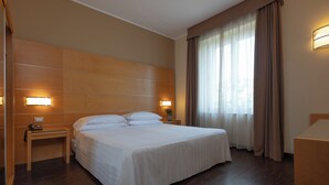 Une chambre d’hôtel avec un grand lit, des lampes de chevet, une table de nuit et une fenêtre avec des rideaux.