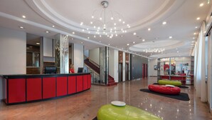 Un hall d’entrée spacieux avec un plafond incurvé, un comptoir d’accueil et un escalier.