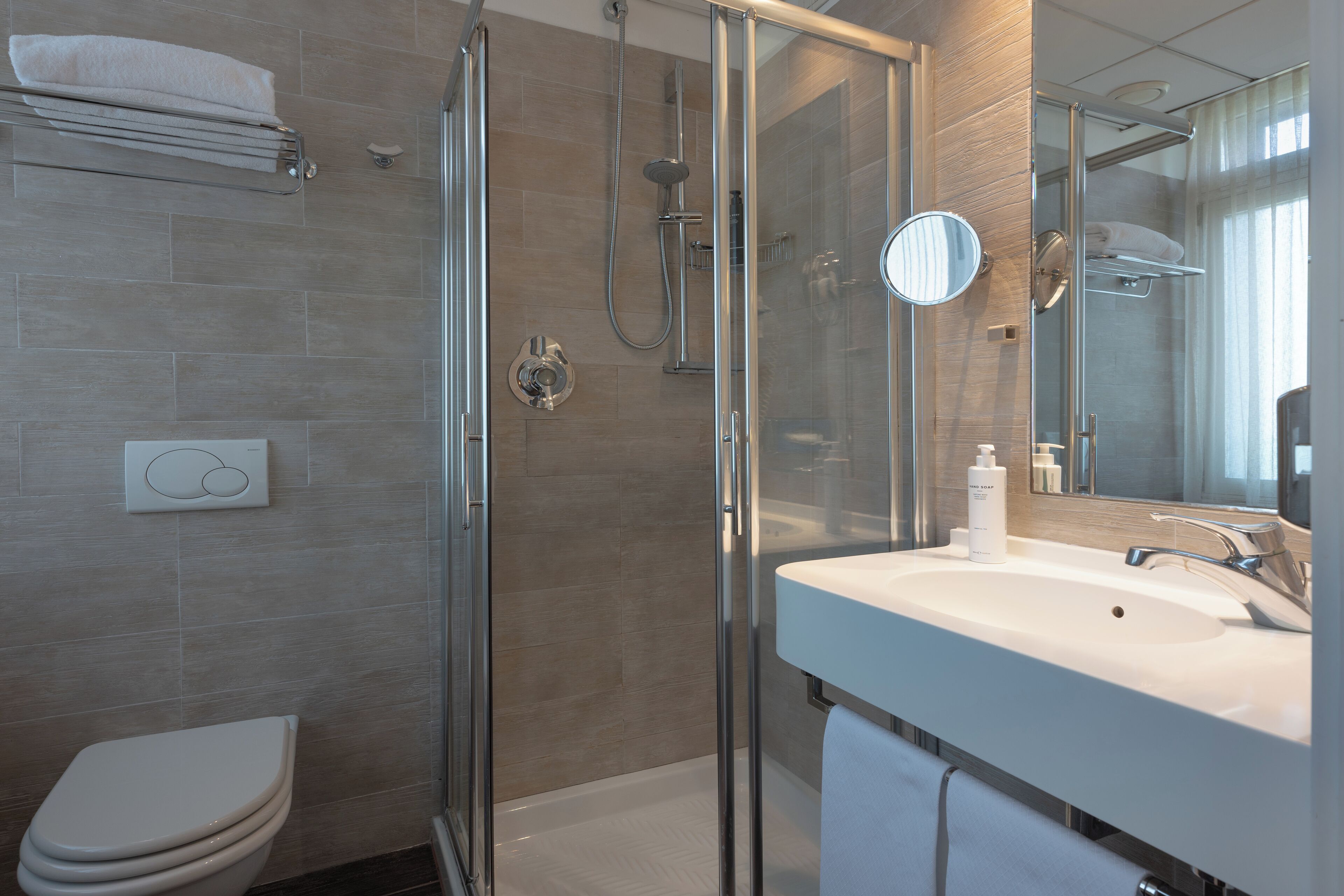 A modern bathroom with a glass shower enclosure, a white sink with a mirror, and a toilet.