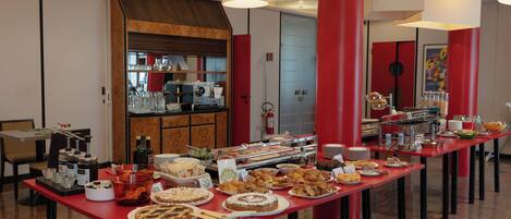 A buffet setup with various food items and beverages, a coffee machine, and a fire extinguisher on the wall.
