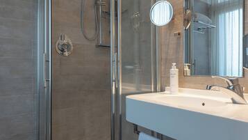 A modern bathroom with a glass-enclosed shower, a white sink, and a large mirror.