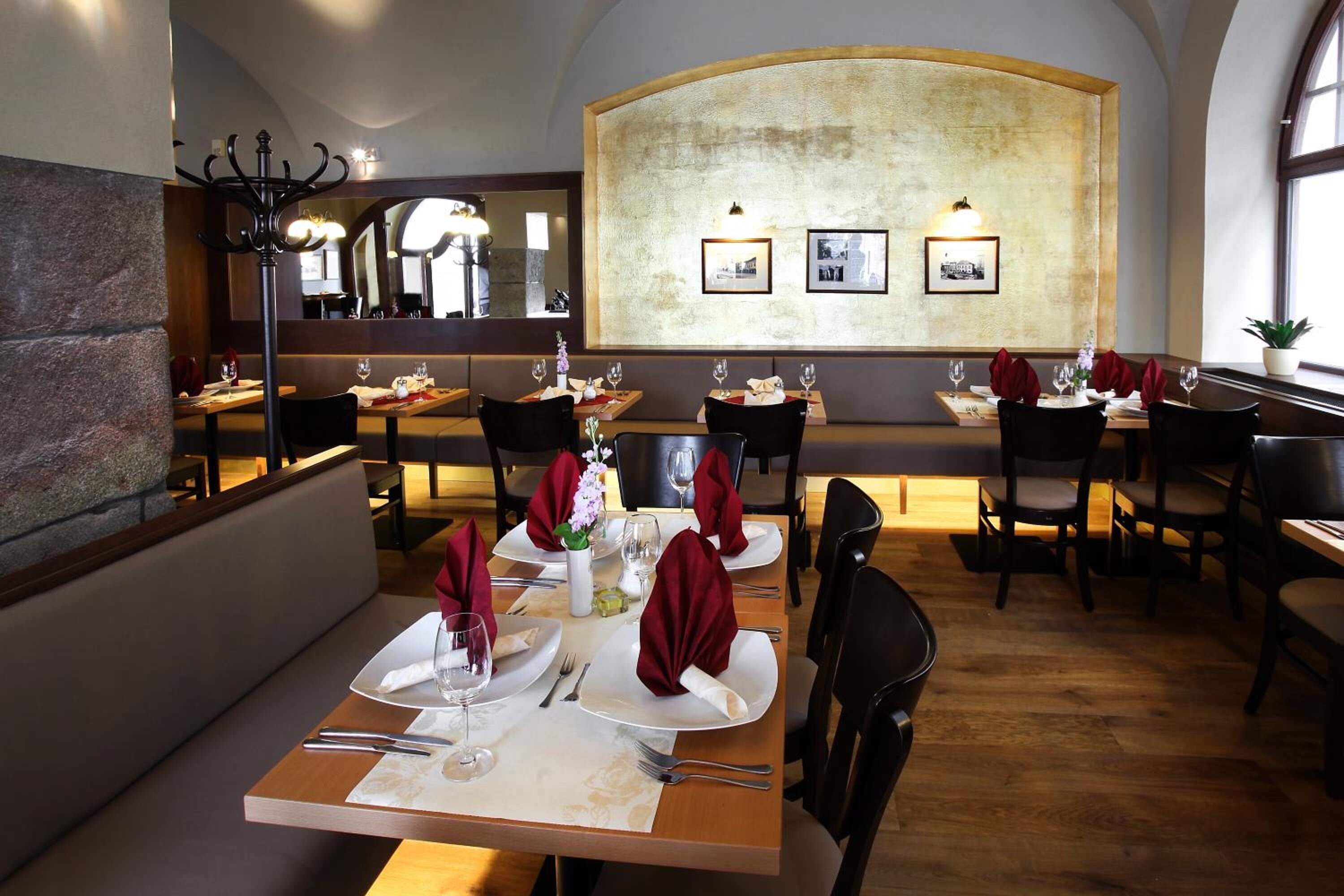 Un restaurant avec des tables et des chaises en bois, un mur en pierre et des tableaux encadrés accrochés au mur.