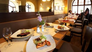 A restaurant interior with tables set for dining, featuring plates of food and wine glasses. - Hotel Zlata Hvezda Trebon (Trebon)