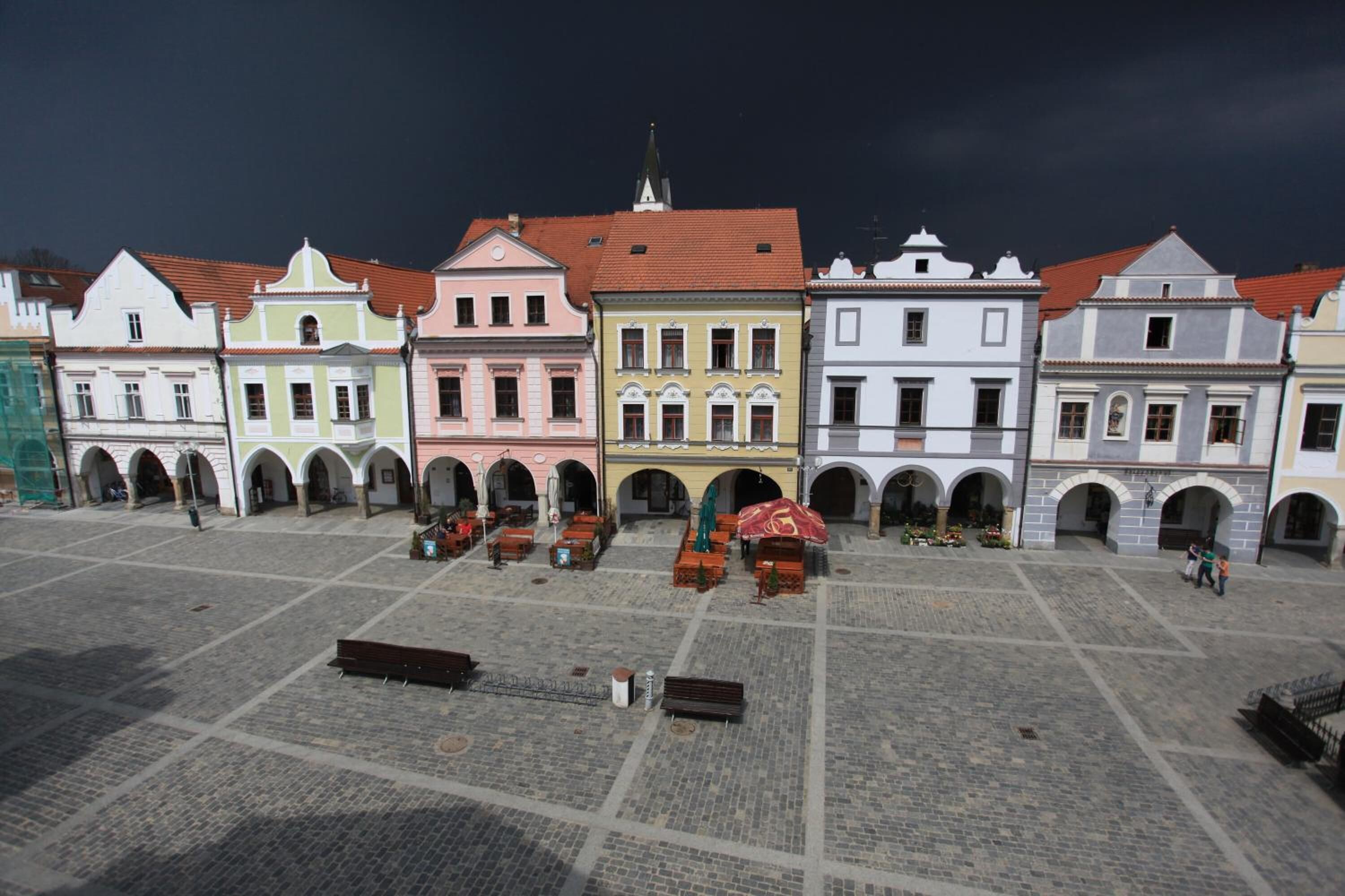 A square with historic buildings, a central fountain, and benches.