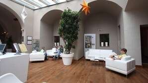 A spacious lobby with a large central plant, white sofas, and a glass ceiling. - Hotel Zlata Hvezda Trebon (Trebon)