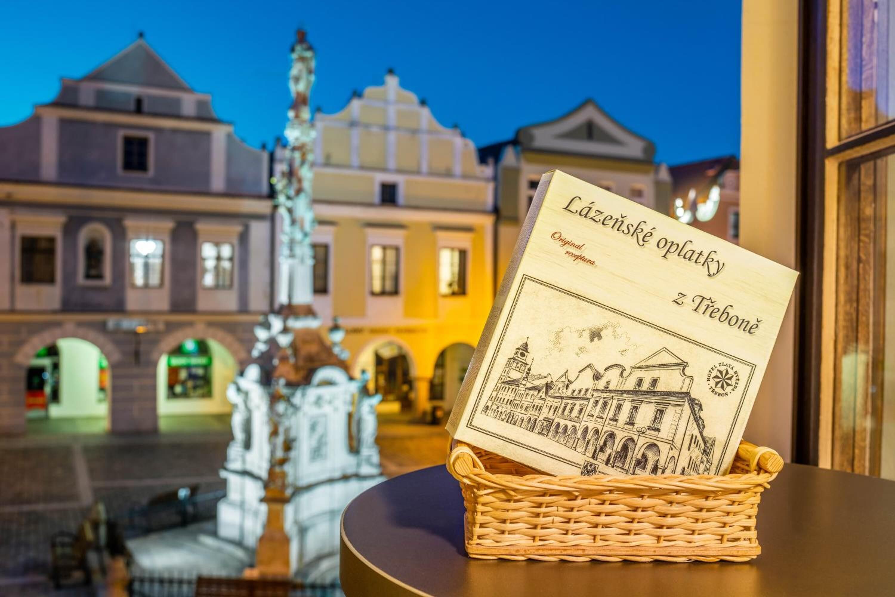 A wicker basket with a book titled "Lazieské oplety z Libonie" on a table.