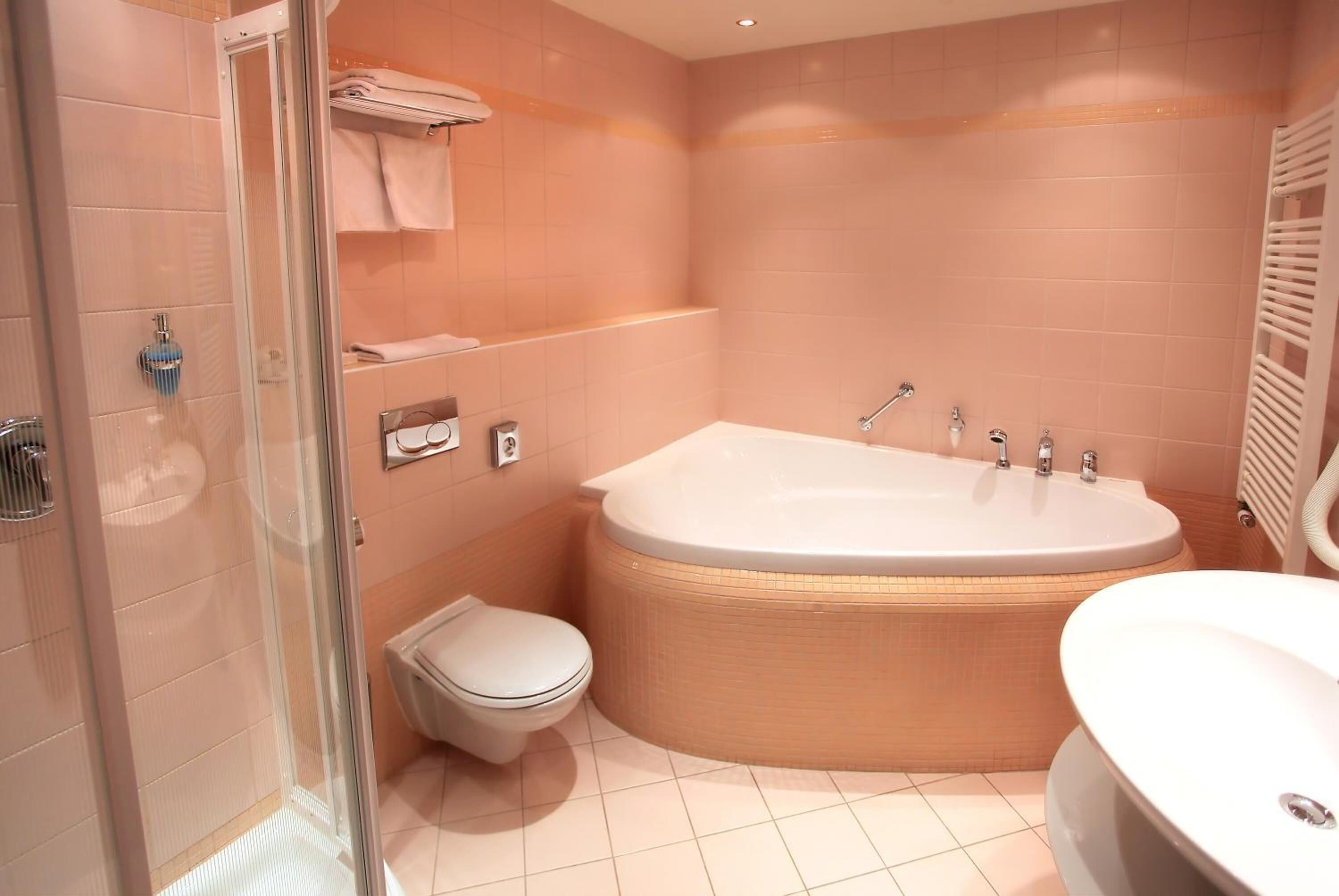Een moderne badkamer met een douchecabine van glas, een vrijstaand bad, een toilet en een wastafel.