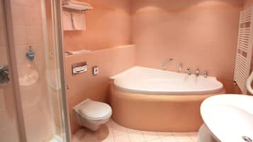 Een moderne badkamer met een douchecabine van glas, een vrijstaand bad, een toilet en een wastafel.