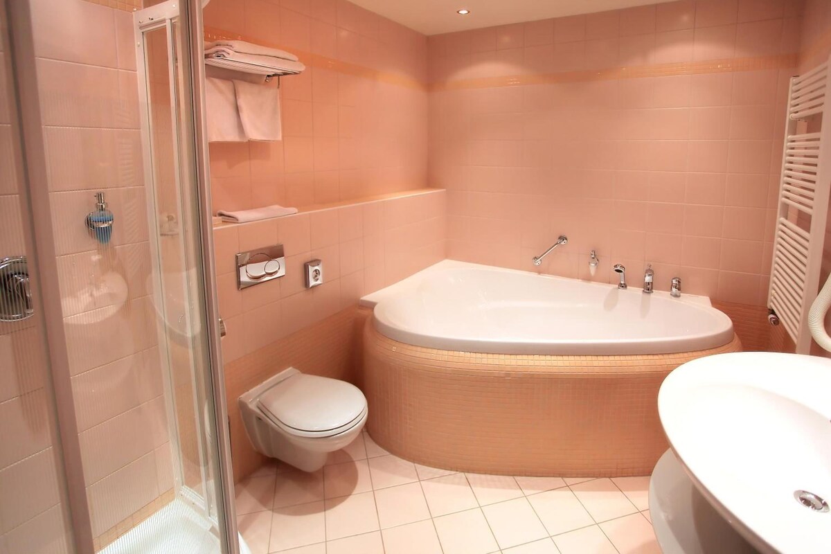 A bathroom with a bathtub, toilet, and shower area.