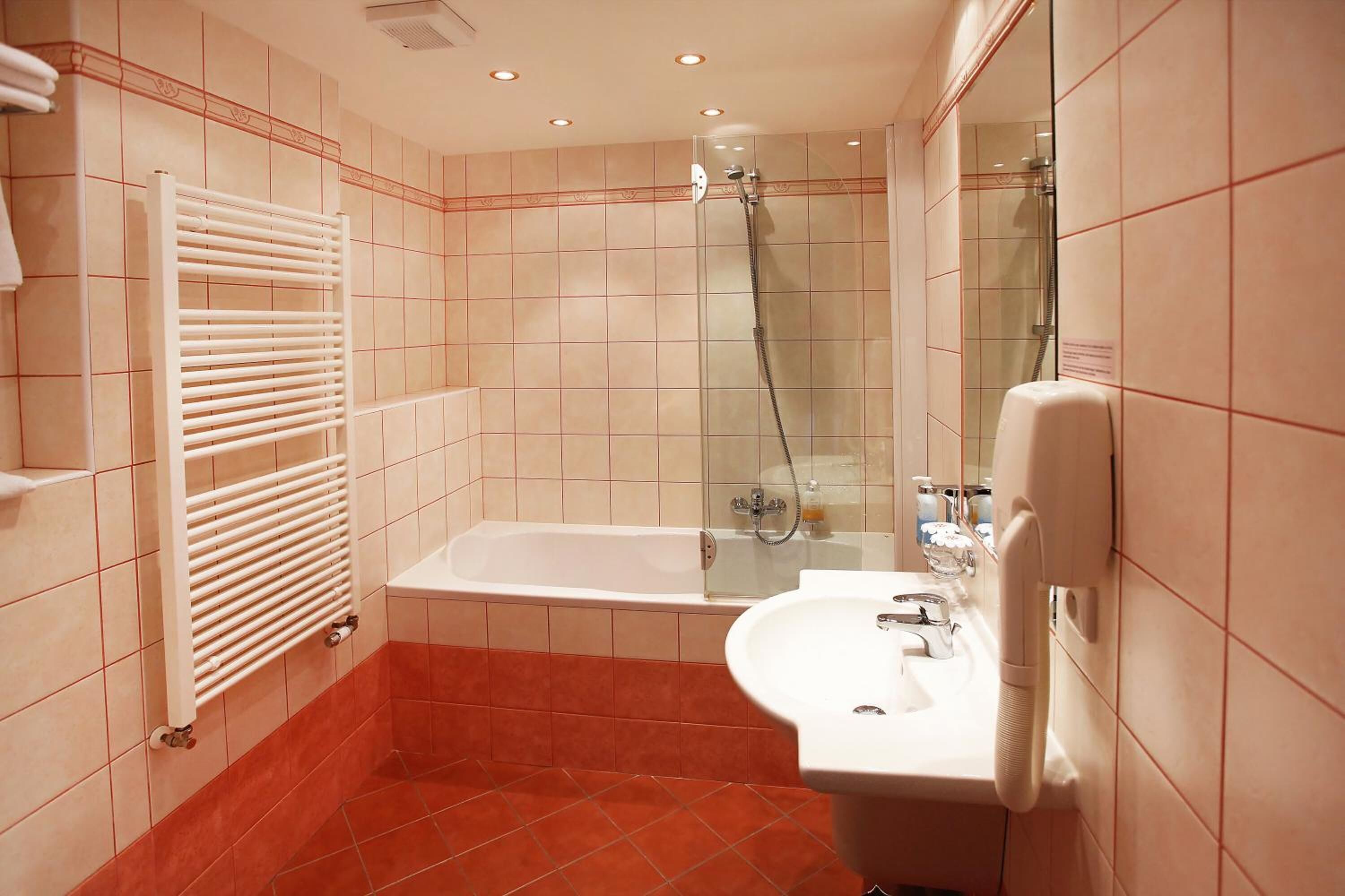 A bathroom with a bathtub, a shower, a sink, and a towel rack.