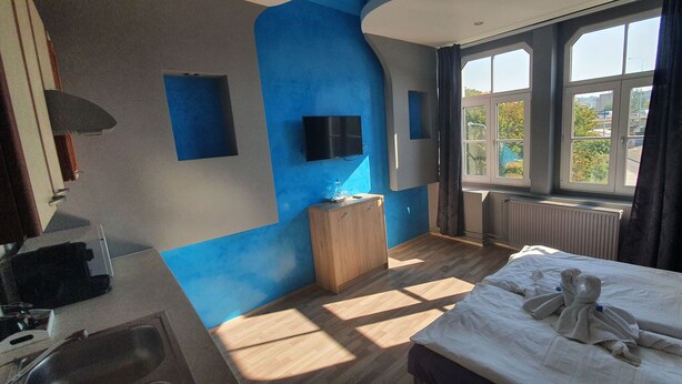 Una camera d'hotel con un letto grande, un armadio in legno, una TV a parete e una finestra con vista sull'esterno.