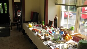 Un buffet per la colazione con diversi cibi e bevande, una televisione e una finestra vista esterna.