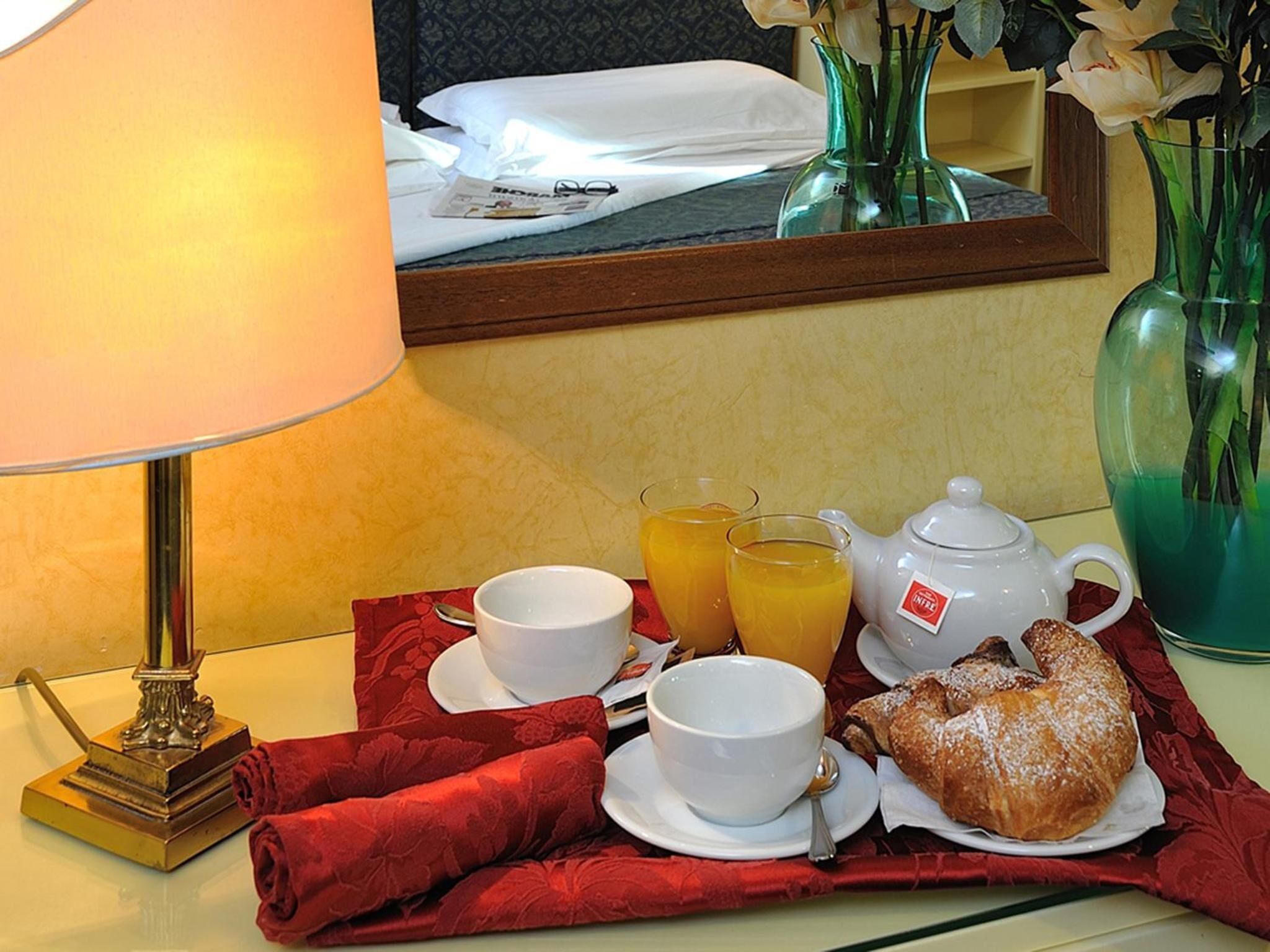 A breakfast setup with a lamp, a mirror, and a table with a red cloth.