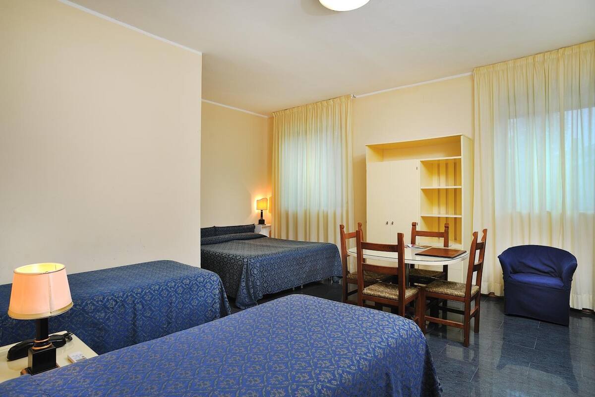 Ein Hotelzimmer mit zwei Betten, einem Schreibtisch, einem Stuhl und einem kleinen Tisch.