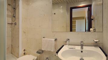 Een badkamer met douche, toilet, bidet, wastafel en spiegel.