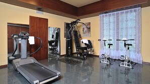 Een fitnessruimte met een loopband, hometrainers en krachtapparaten.