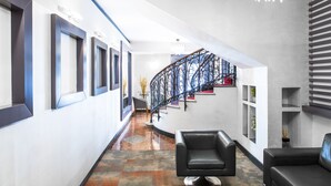 A modern interior with a staircase, black leather chairs, and a chandelier. - Hotel Piazza Di Spagna (Rome)