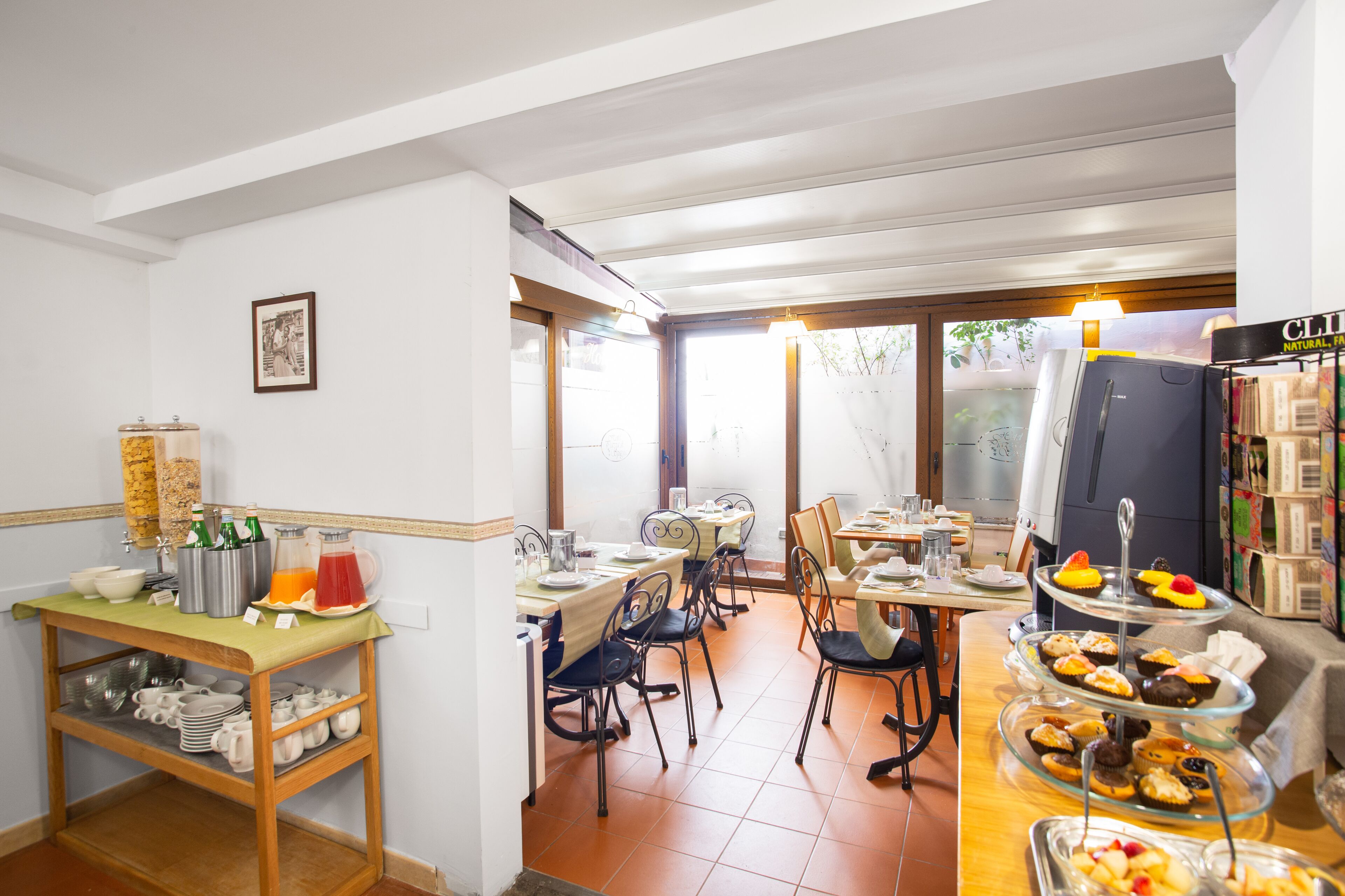 A dining area with a buffet setup, including a beverage station and a variety of food items on display.