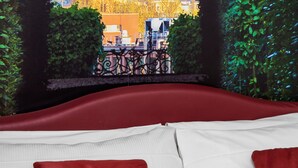 A bed with red and white pillows, a view of a large dome building, and greenery framing the window. - Hotel Piazza Di Spagna (Rome)