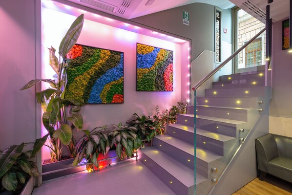 A staircase with glass railings and a plant-lined landing. - Al Manthia Hotel - Trevi Hotels Group (Rome)