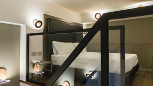 Un dormitorio moderno con cama, mesita de noche y escalera de cristal.