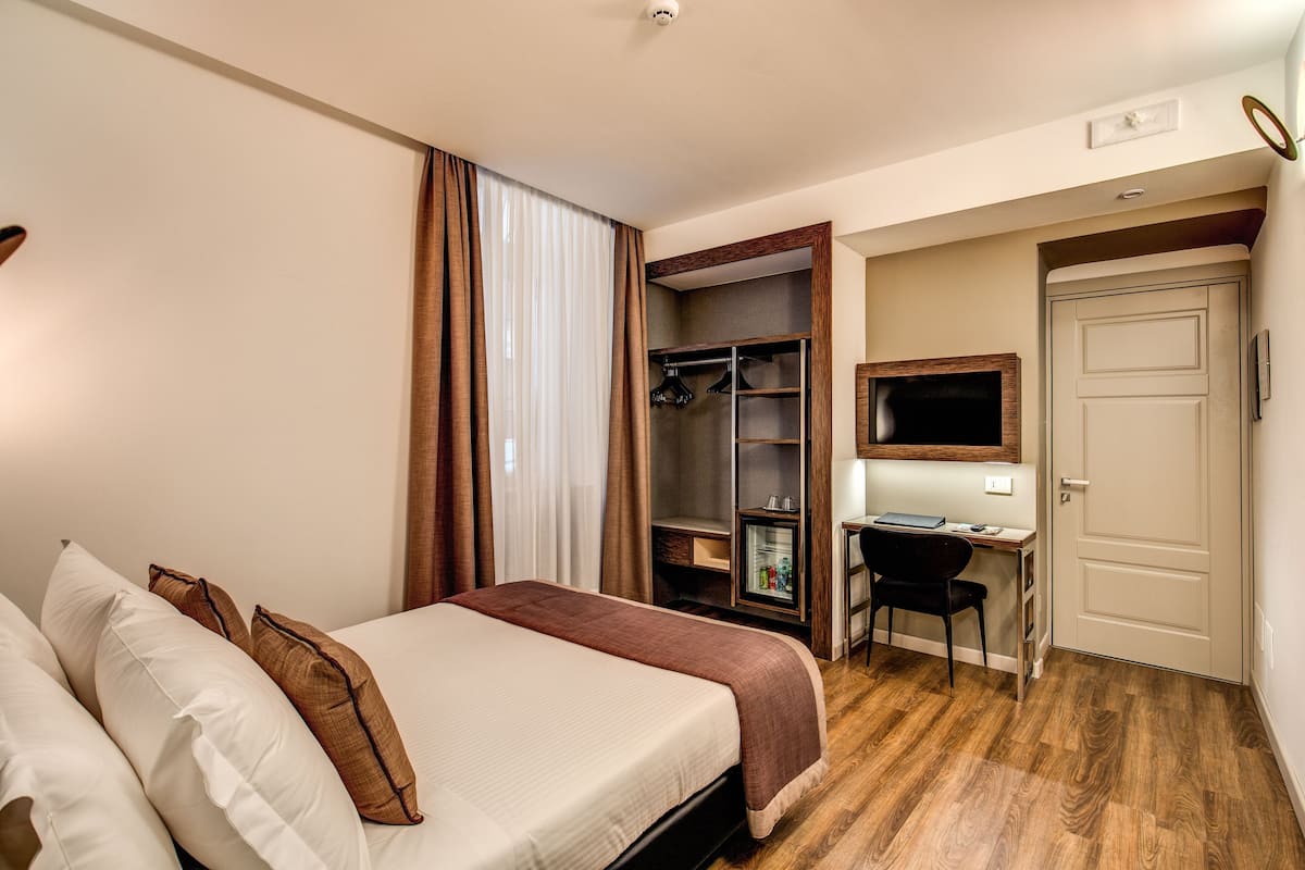 Ett hotellrum med en säng, ett skrivbord, en TV och en garderob.