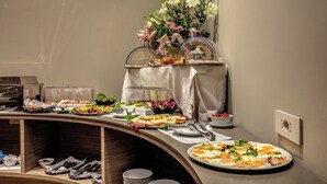 Montaje de bufé con diferentes alimentos y un centro de mesa floral.