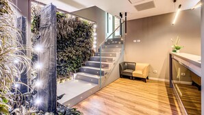 Un interior moderno con una escalera que lleva a un balcón, una zona de estar y un mostrador de recepción.