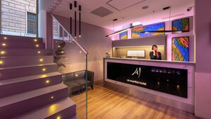 Una recepción de hotel con diseño moderno, una escalera con peldaños iluminados y vistas al exterior.