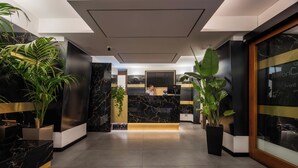 Ein Hotel-Empfangsbereich mit Marmorzauber, Blumentöpfen und modernem Interieur.