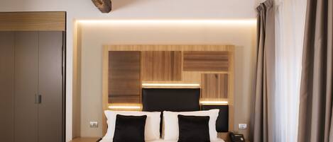 Habitación de hotel con una cama grande, cabecera de madera, mesitas de noche y un armario.