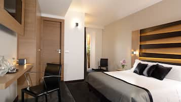 A modern hotel room with a bed, a desk, a chair, and a nightstand.