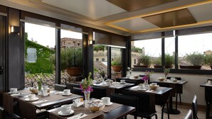 Ein modernes Restaurant mit gedeckten Tischen, großen Fenstern mit Blick auf die Stadt und Zimmerpflanzen.