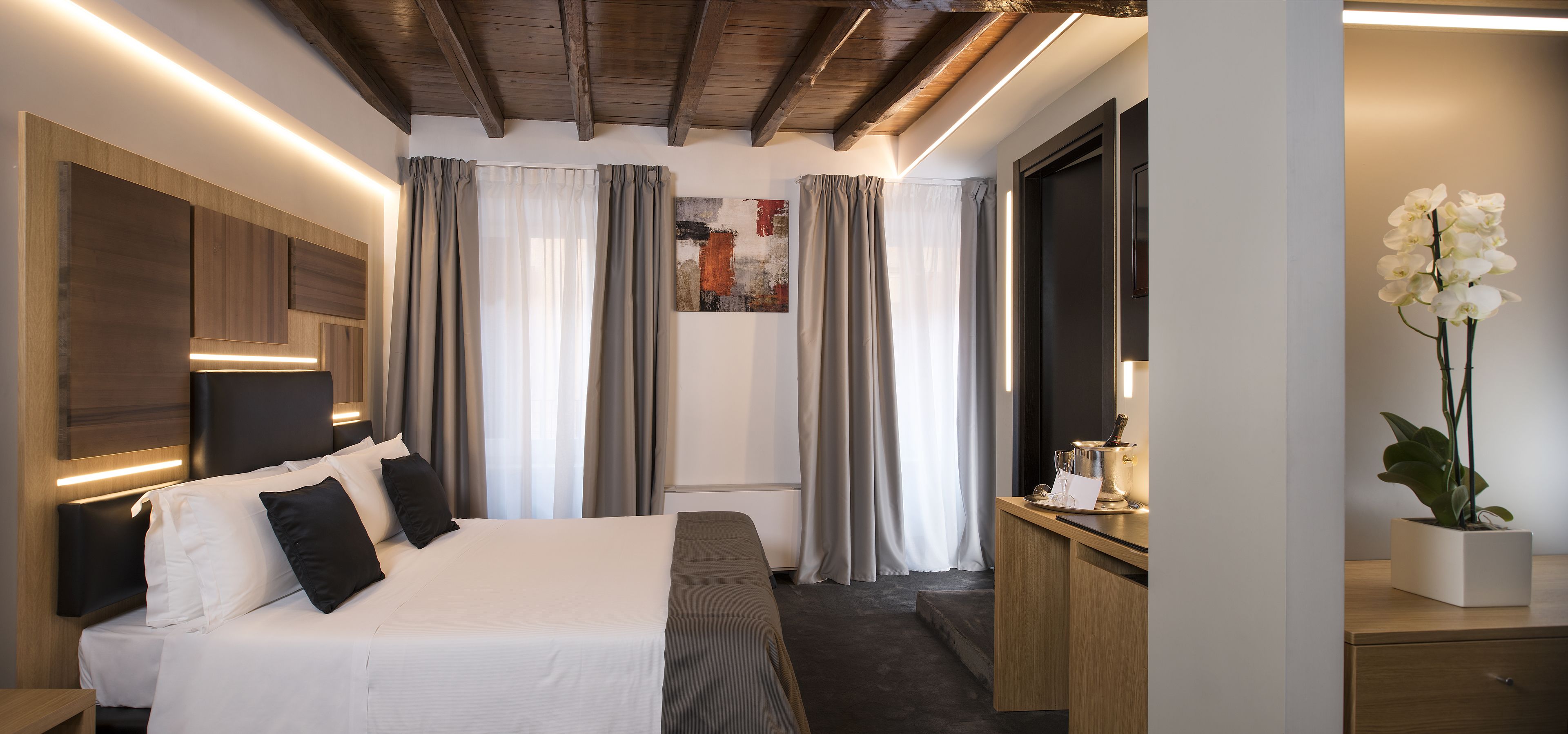 Een moderne hotelkamer met een groot bed, een bureau en een kamerplant.