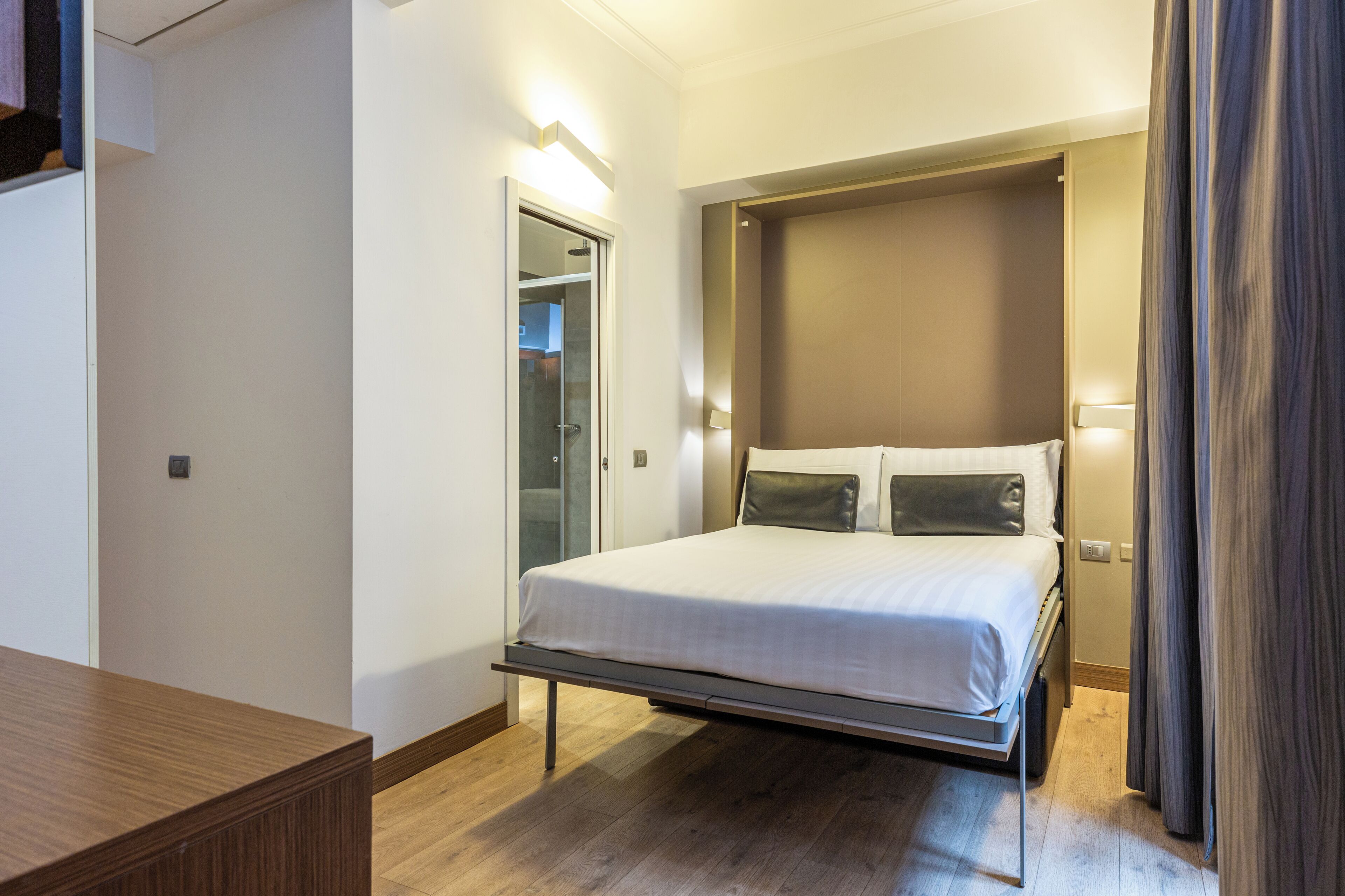 Een moderne slaapkamer met een bed, nachtkastjes, een kledingkast en een deur.