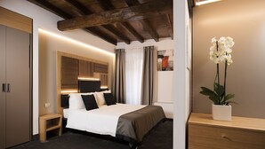 Ein modernes Hotelzimmer mit einem großen Bett, einem Nachttisch, einem Schreibtisch und einer Topfpflanze.