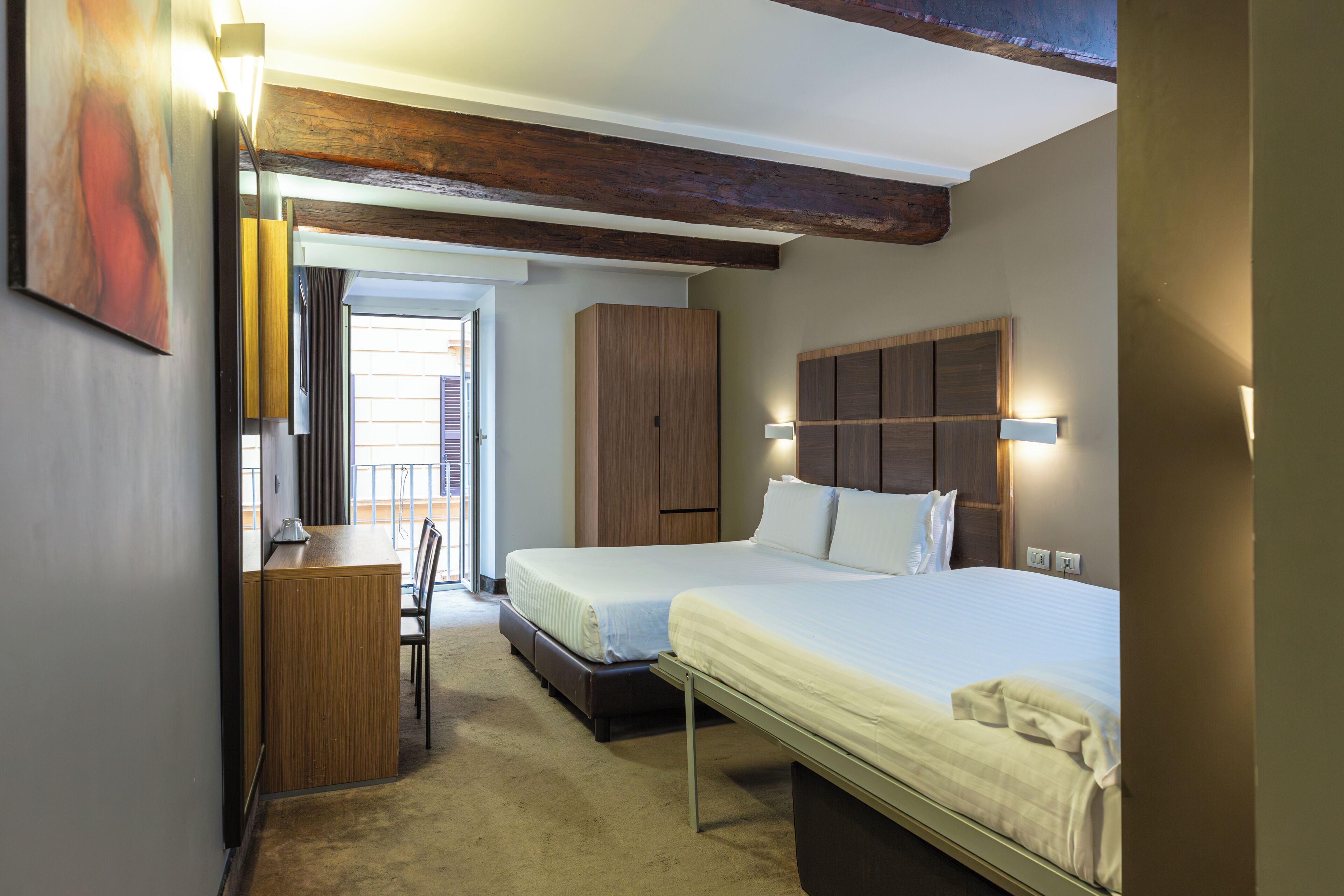 A hotel room with two beds, a desk, and a wardrobe.