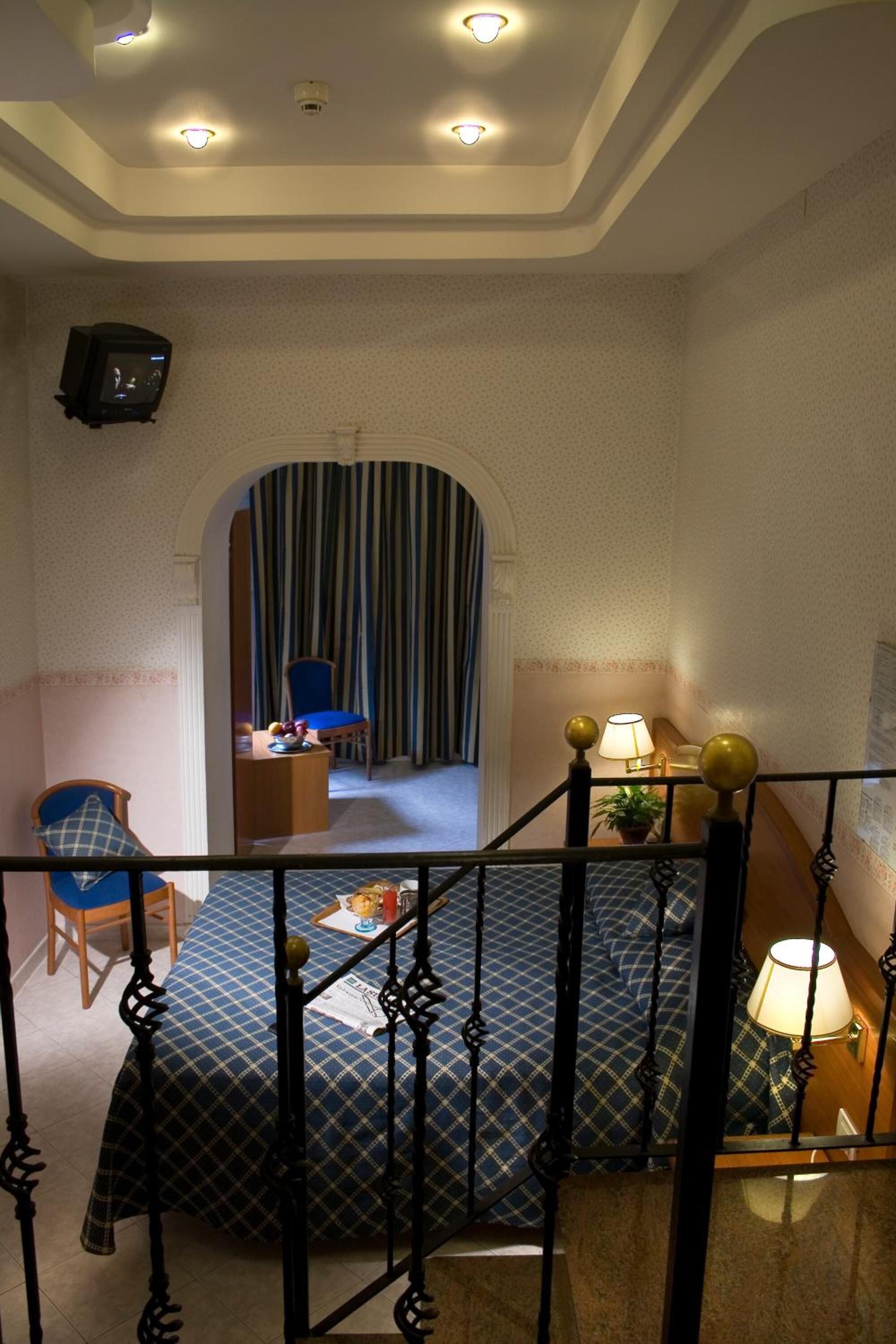 Habitación de hotel con cama, escritorio, silla, televisor y una escalera.