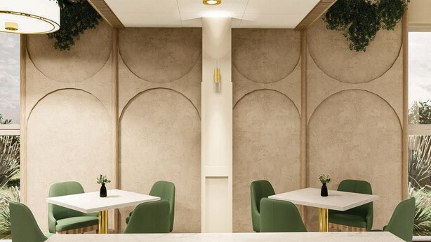 Interior de un restaurante con una columna central, sillas verdes, mesas blancas y plantas decorativas.