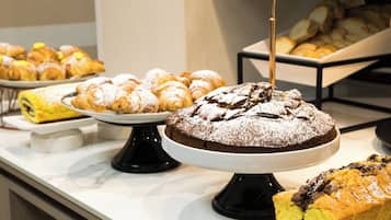A buffet with various baked goods including pastries, a chocolate cake, and a yellow cake.