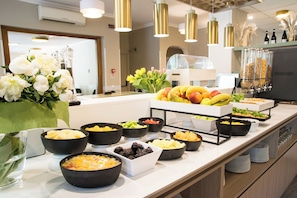 A buffet with various food items and a flower arrangement.