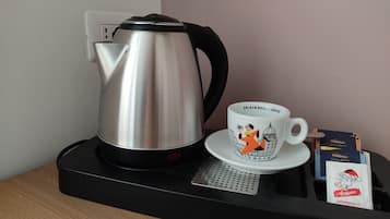 A coffee maker, a mug with a coffee cup illustration, and two coffee packets on a tray.
