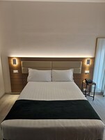 Una camera d'albergo con un letto grande, un comodino con il telefono e luci a parete.