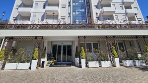 Un edificio moderno con varios balcones y una fachada central de vidrio.