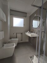 Un bagno moderno con vasca, water, lavandino e doccia.