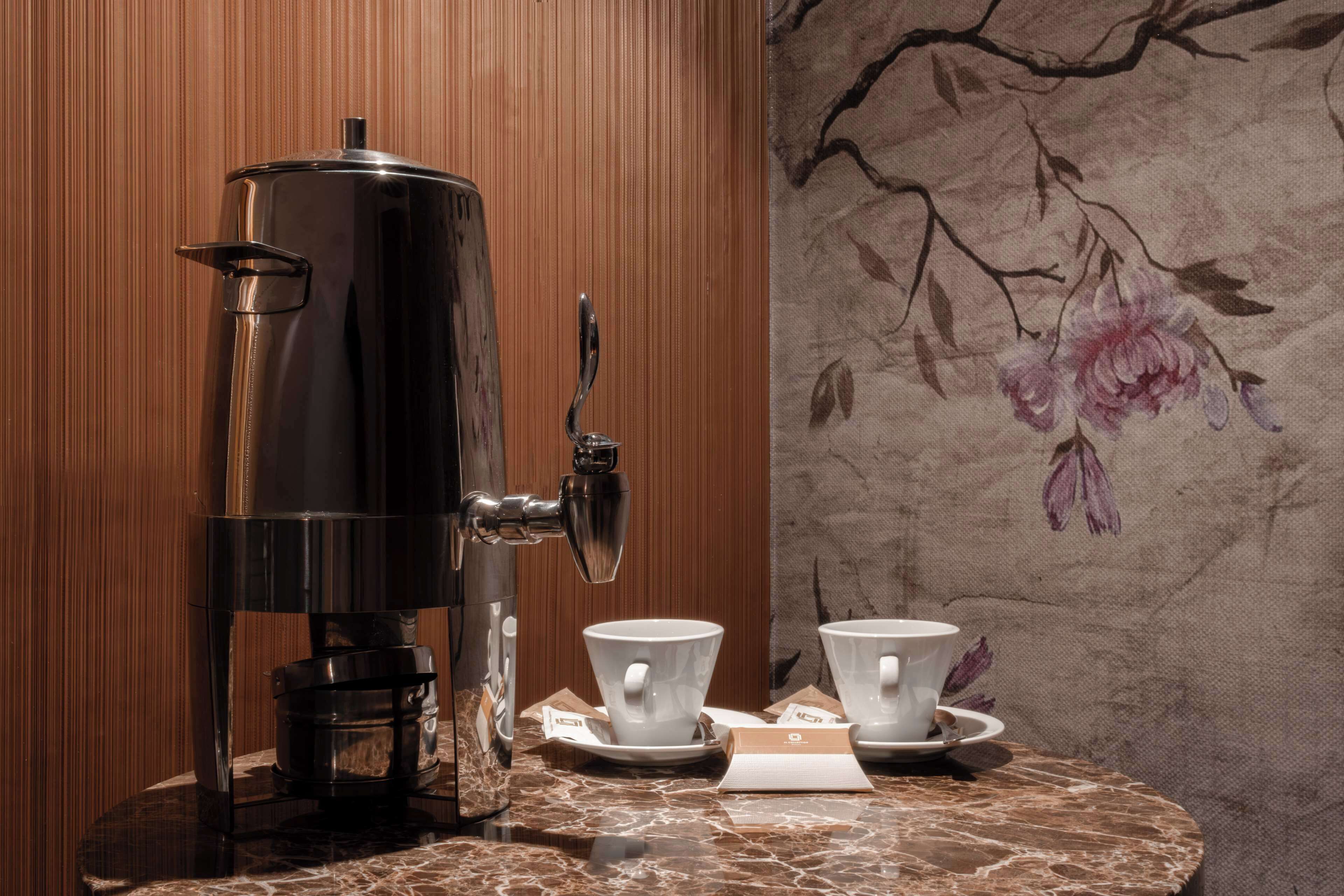 A coffee machine with two cups and saucers on a marble table.